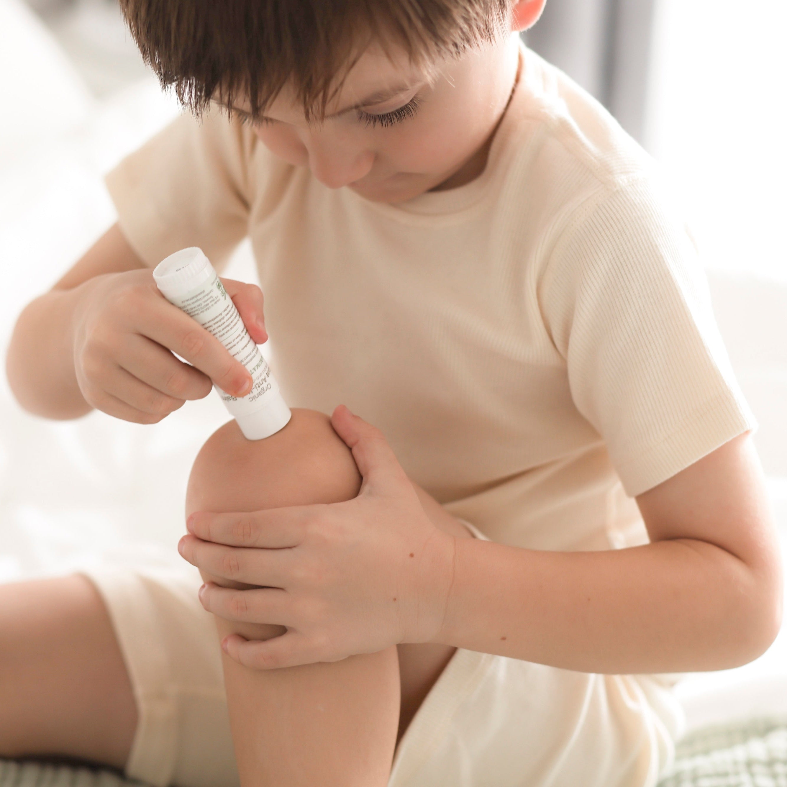 Boy applying USDA certified organic anti-itch cream to his knee